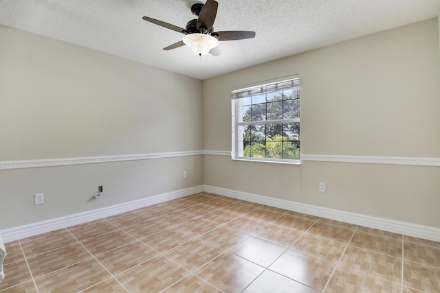 empty room with a ceiling fan, tile patterned flooring, baseboards, and a textured ceiling