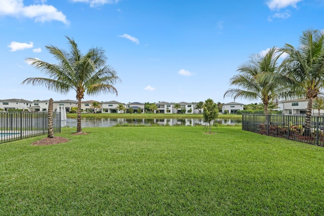 view of yard featuring a residential view, a water view, and fence