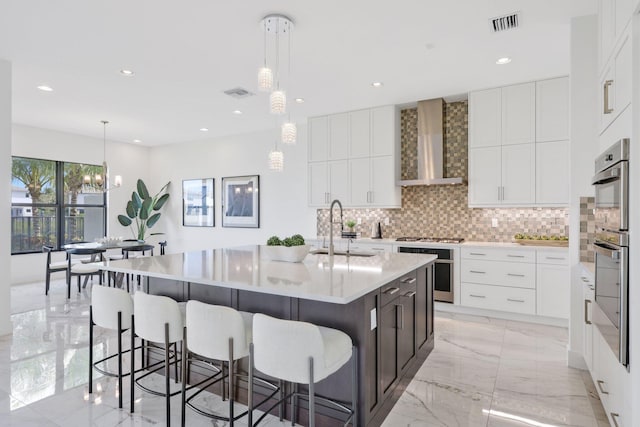 kitchen featuring marble finish floor, a sink, wall chimney range hood, and decorative backsplash