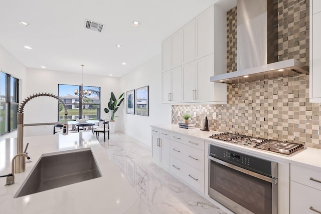 kitchen featuring marble finish floor, stainless steel appliances, visible vents, a sink, and wall chimney exhaust hood