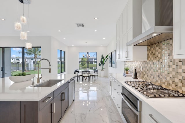 kitchen with a sink, visible vents, marble finish floor, appliances with stainless steel finishes, and wall chimney exhaust hood