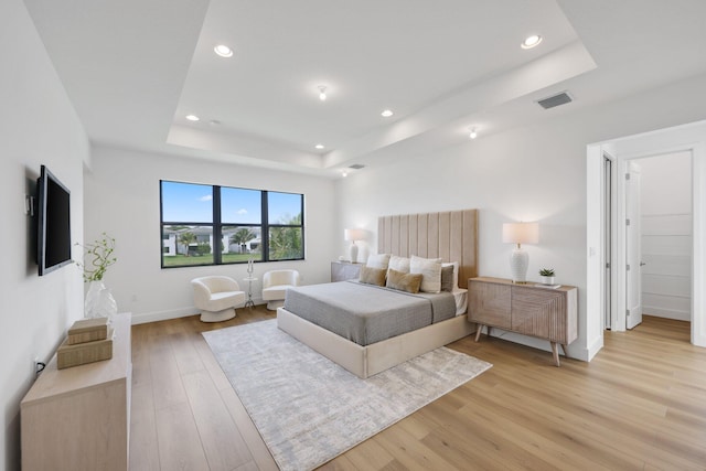 bedroom with recessed lighting, a raised ceiling, visible vents, and light wood-style flooring