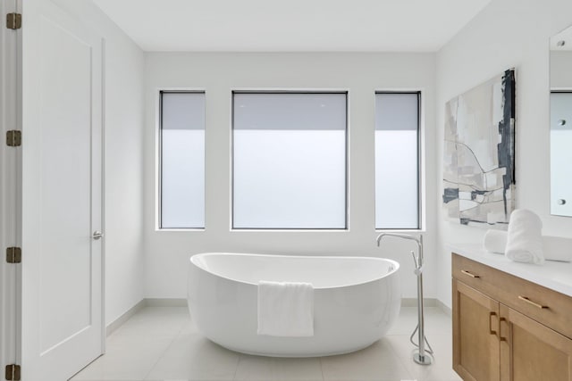 bathroom with a freestanding bath, vanity, baseboards, and tile patterned floors