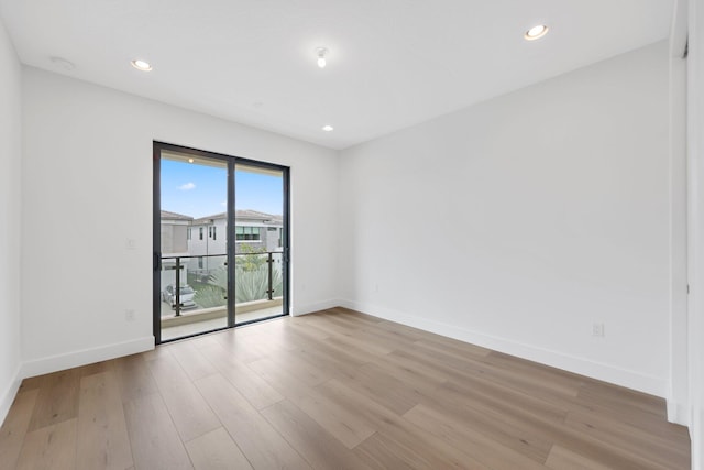 empty room with light wood finished floors, recessed lighting, and baseboards