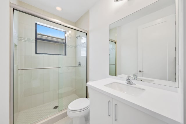 bathroom with vanity, a shower stall, and toilet