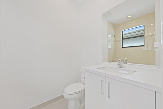 bathroom featuring baseboards, tiled shower, vanity, and toilet