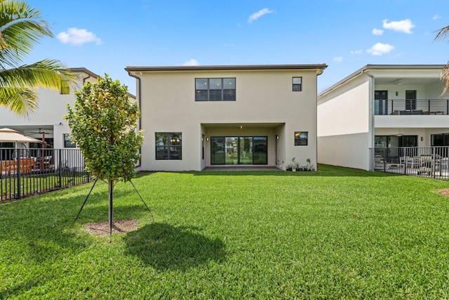 rear view of property with stucco siding, fence, and a yard