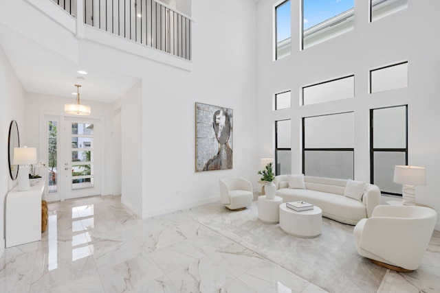 living area featuring a healthy amount of sunlight, marble finish floor, and baseboards