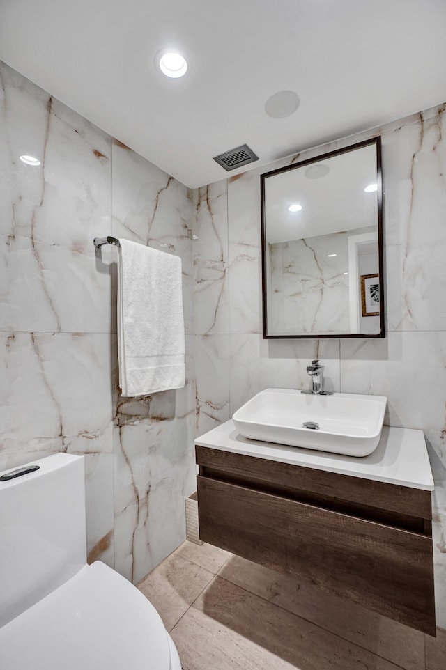 bathroom with tile walls, recessed lighting, visible vents, toilet, and vanity