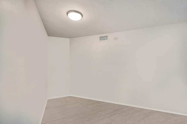 unfurnished room featuring light wood-type flooring, visible vents, and baseboards