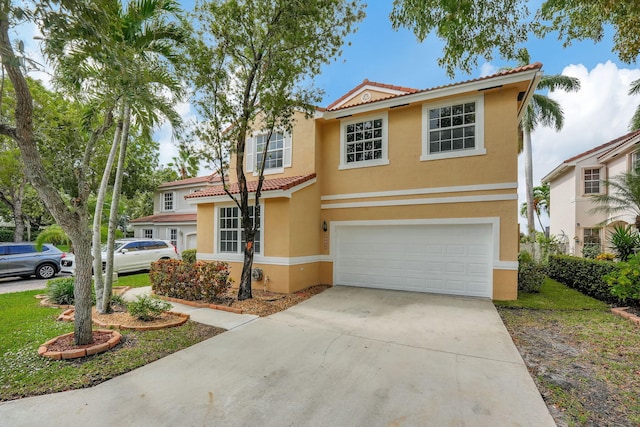 mediterranean / spanish house with a tiled roof, an attached garage, driveway, and stucco siding