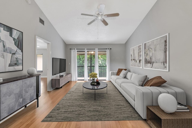 living room with high vaulted ceiling, light wood-style flooring, visible vents, and a ceiling fan