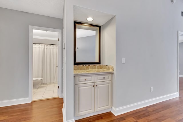 hallway featuring visible vents, light wood-style flooring, and baseboards