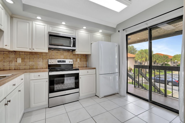 kitchen with tasteful backsplash, stainless steel appliances, light countertops, white cabinetry, and recessed lighting