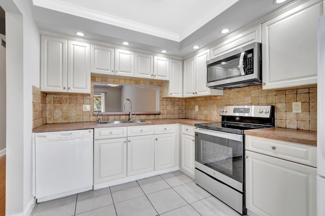 kitchen featuring crown molding, stainless steel appliances, tasteful backsplash, white cabinetry, and a sink