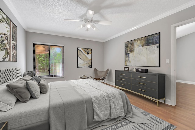 bedroom with baseboards, a textured ceiling, ornamental molding, and wood finished floors