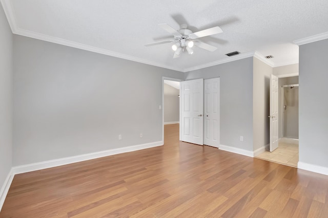 unfurnished bedroom with a textured ceiling, visible vents, baseboards, light wood-style floors, and crown molding