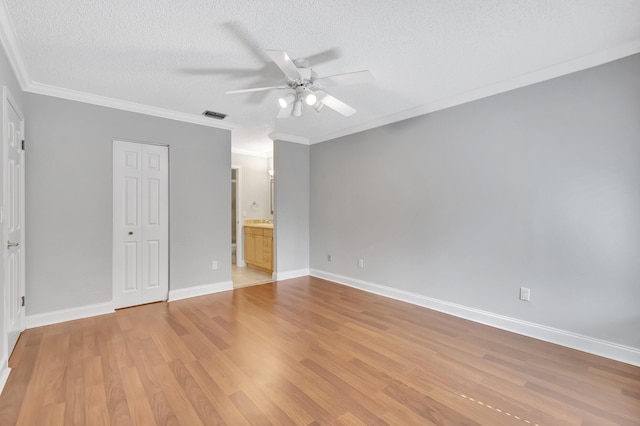 unfurnished bedroom featuring light wood finished floors, baseboards, visible vents, a textured ceiling, and crown molding