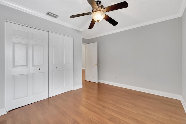 unfurnished bedroom with light wood-type flooring, visible vents, a closet, and ornamental molding