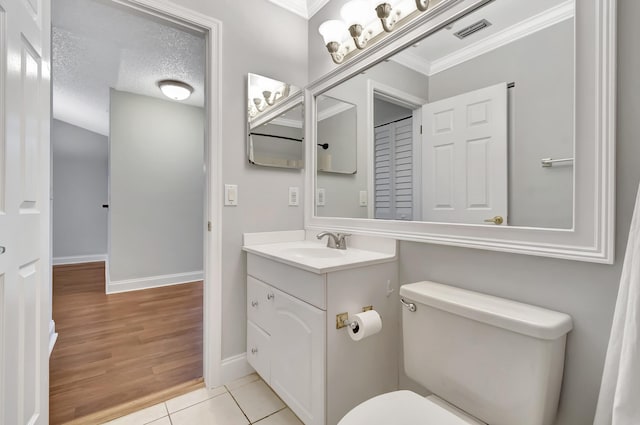 half bath with a textured ceiling, tile patterned flooring, toilet, vanity, and visible vents