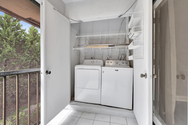 clothes washing area with washer and dryer, laundry area, and light tile patterned flooring