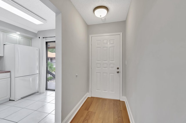 doorway to outside with a textured ceiling, baseboards, and light wood finished floors