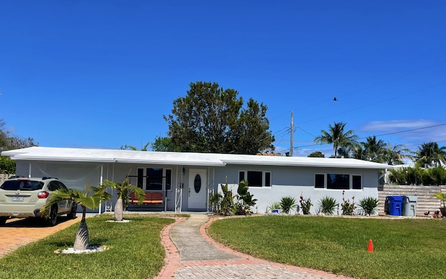 ranch-style home featuring a front yard, a porch, a carport, and stucco siding