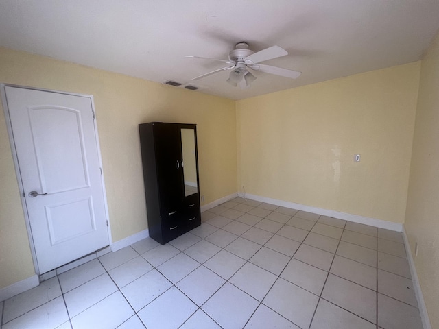 empty room featuring visible vents, light tile patterned flooring, a ceiling fan, and baseboards