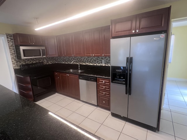 kitchen with light tile patterned floors, tasteful backsplash, dark stone counters, stainless steel appliances, and a sink