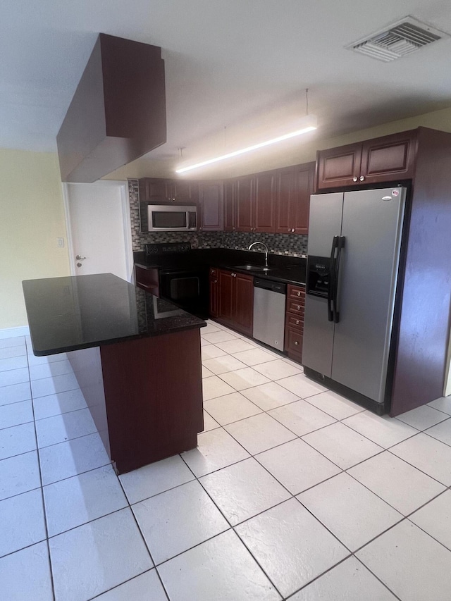 kitchen with light tile patterned floors, stainless steel appliances, visible vents, a center island, and tasteful backsplash