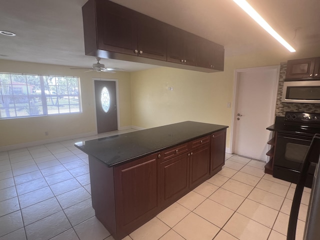 kitchen with light tile patterned floors, electric range, a ceiling fan, dark countertops, and stainless steel microwave