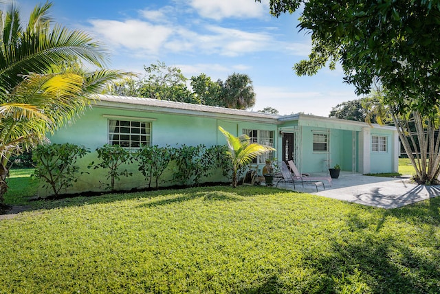 back of property with a yard, a patio area, and stucco siding