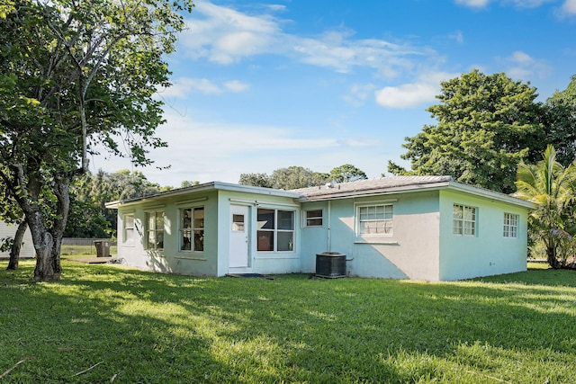 back of house featuring cooling unit, a yard, and stucco siding