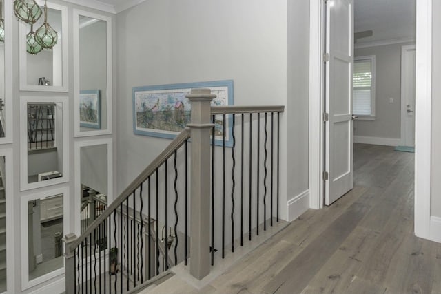 staircase featuring baseboards, wood finished floors, and crown molding