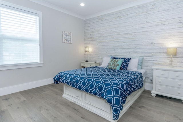 bedroom featuring crown molding, light wood finished floors, recessed lighting, an accent wall, and baseboards