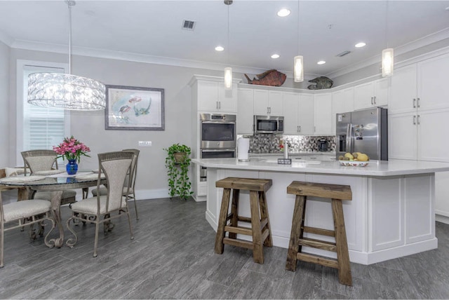 kitchen featuring ornamental molding, appliances with stainless steel finishes, white cabinets, and tasteful backsplash