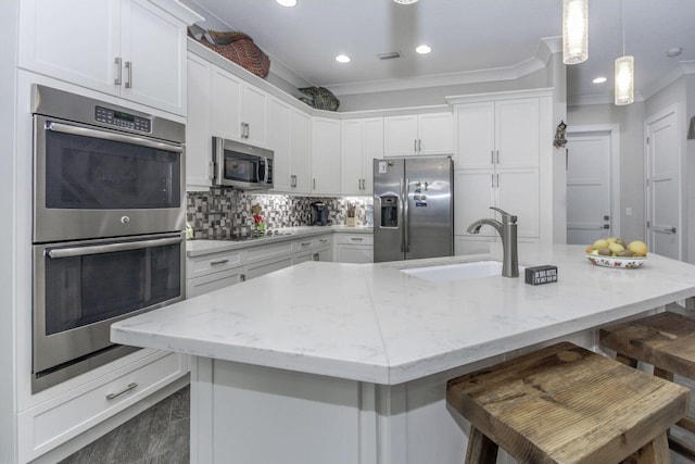 kitchen with tasteful backsplash, white cabinets, stainless steel appliances, a kitchen bar, and a sink