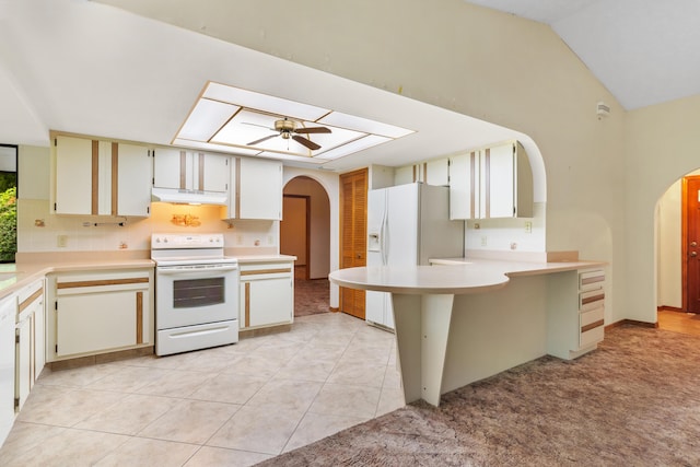 kitchen featuring arched walkways, light countertops, white appliances, and a peninsula