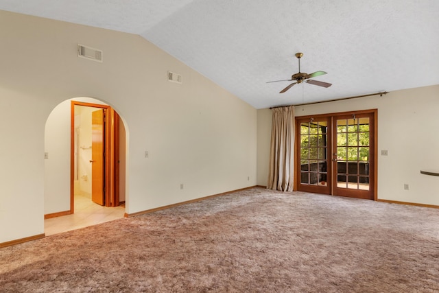 empty room with visible vents, arched walkways, a ceiling fan, and light colored carpet