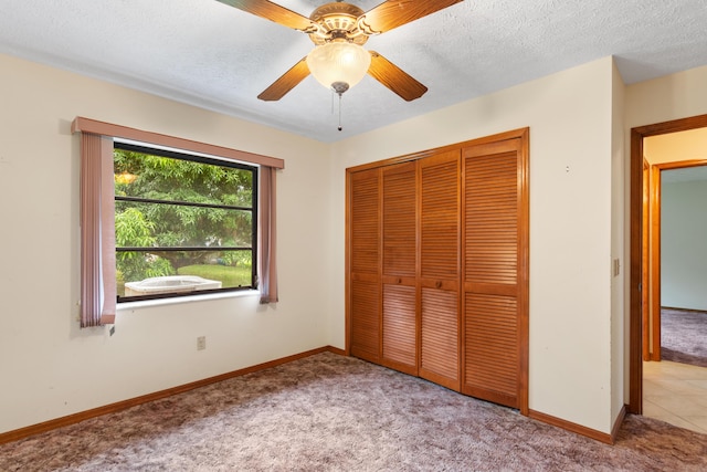 unfurnished bedroom with a closet, carpet flooring, ceiling fan, a textured ceiling, and baseboards