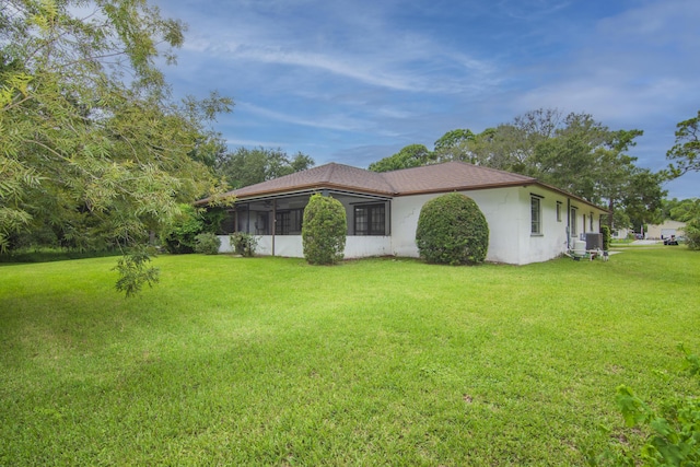 view of side of home with a sunroom, cooling unit, a lawn, and stucco siding