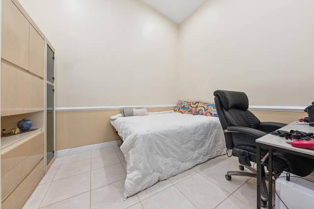 bedroom featuring lofted ceiling, baseboards, and light tile patterned flooring