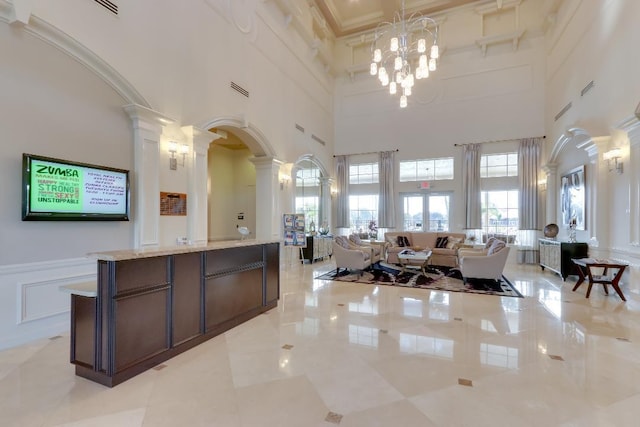 interior space featuring decorative columns, visible vents, arched walkways, and a notable chandelier