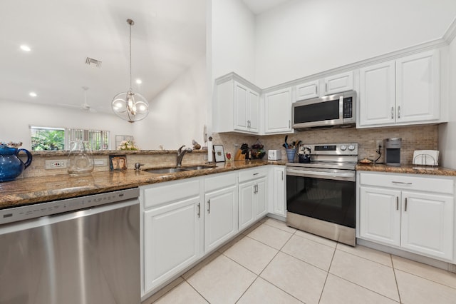 kitchen featuring visible vents, appliances with stainless steel finishes, white cabinetry, a sink, and dark stone counters