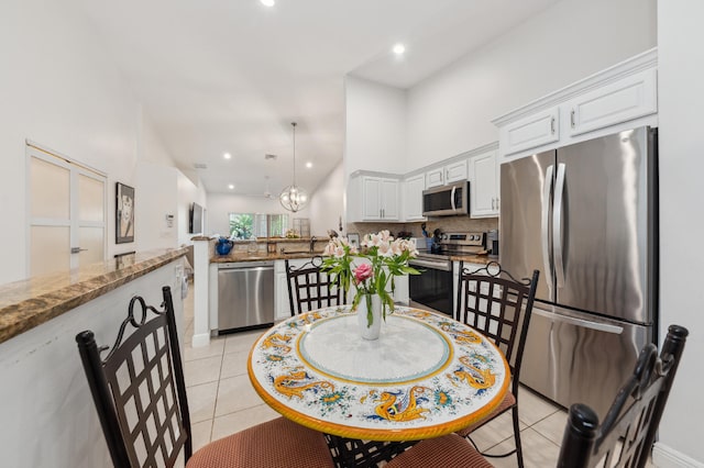 dining room with a towering ceiling, an inviting chandelier, recessed lighting, and light tile patterned flooring