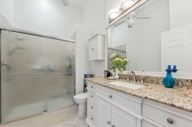 bathroom with tile patterned flooring, toilet, vanity, a ceiling fan, and a shower stall