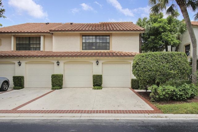 mediterranean / spanish-style house featuring a garage, driveway, and stucco siding