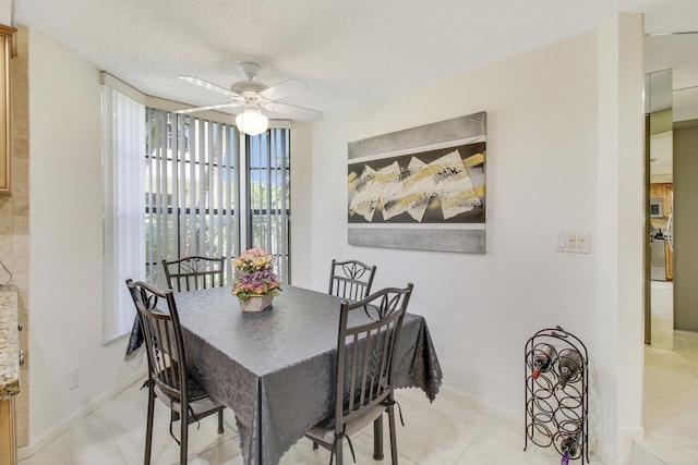 dining space featuring ceiling fan, baseboards, a textured ceiling, and light tile patterned flooring