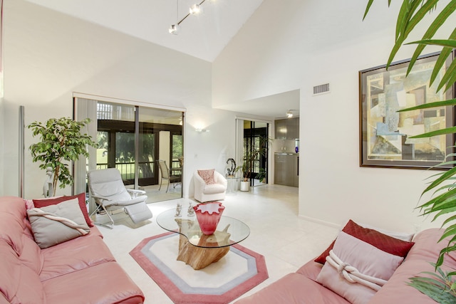 tiled living area featuring high vaulted ceiling, visible vents, and baseboards