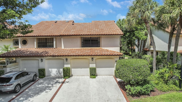 mediterranean / spanish home featuring a garage, a tiled roof, and stucco siding